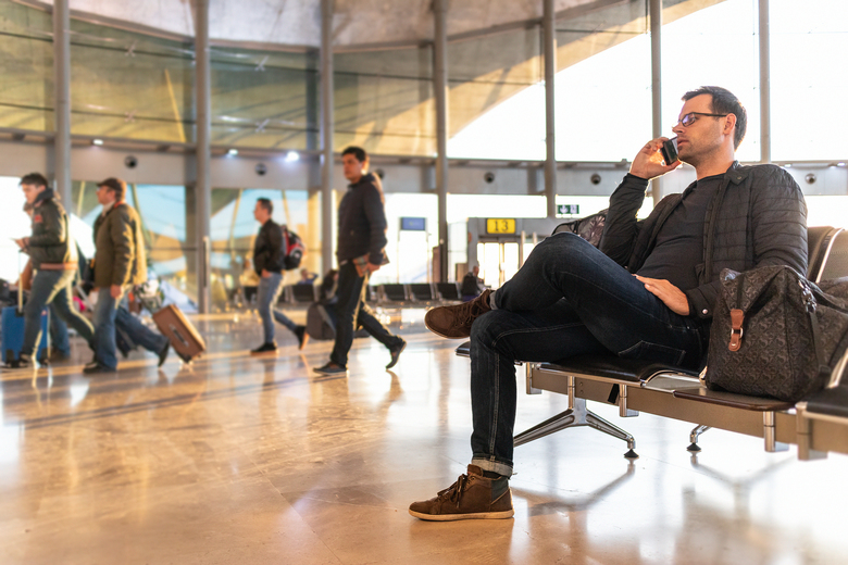 Male Traveler Talking On His Cell Phone While Waiting To Board A