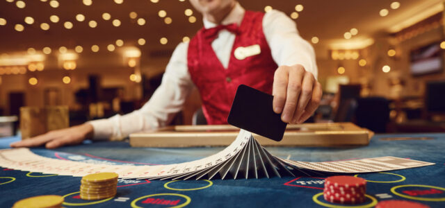 The croupier holds poker cards in his hands at a clean table in a casino.