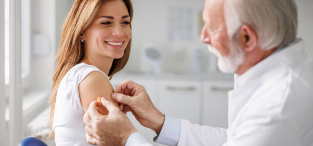 Doctor applying medical patch to female patient after vaccination