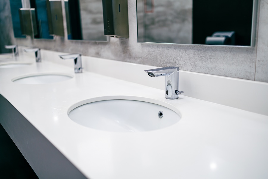 public toilet with sinks for washing hands. a row of sinks and faucets in the bathroom