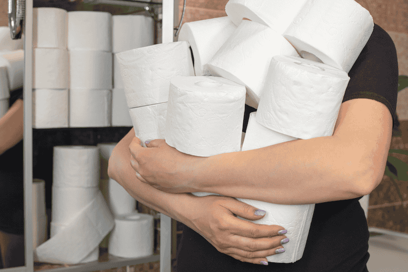 An Enviro-Master technician wearing a black shirt holds several roles of toilet paper.